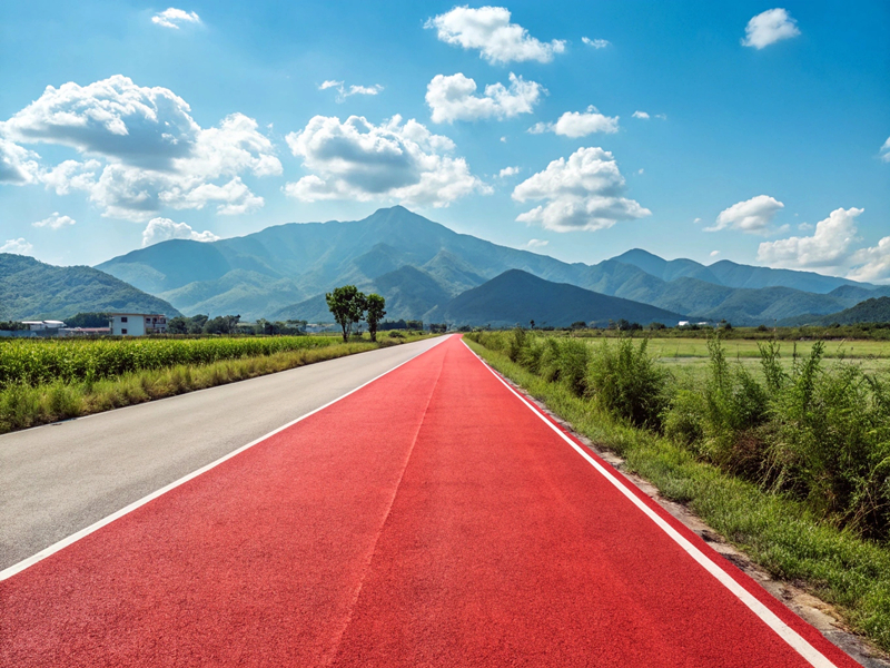 Red asphalt road in countryside with mountains and blue sky